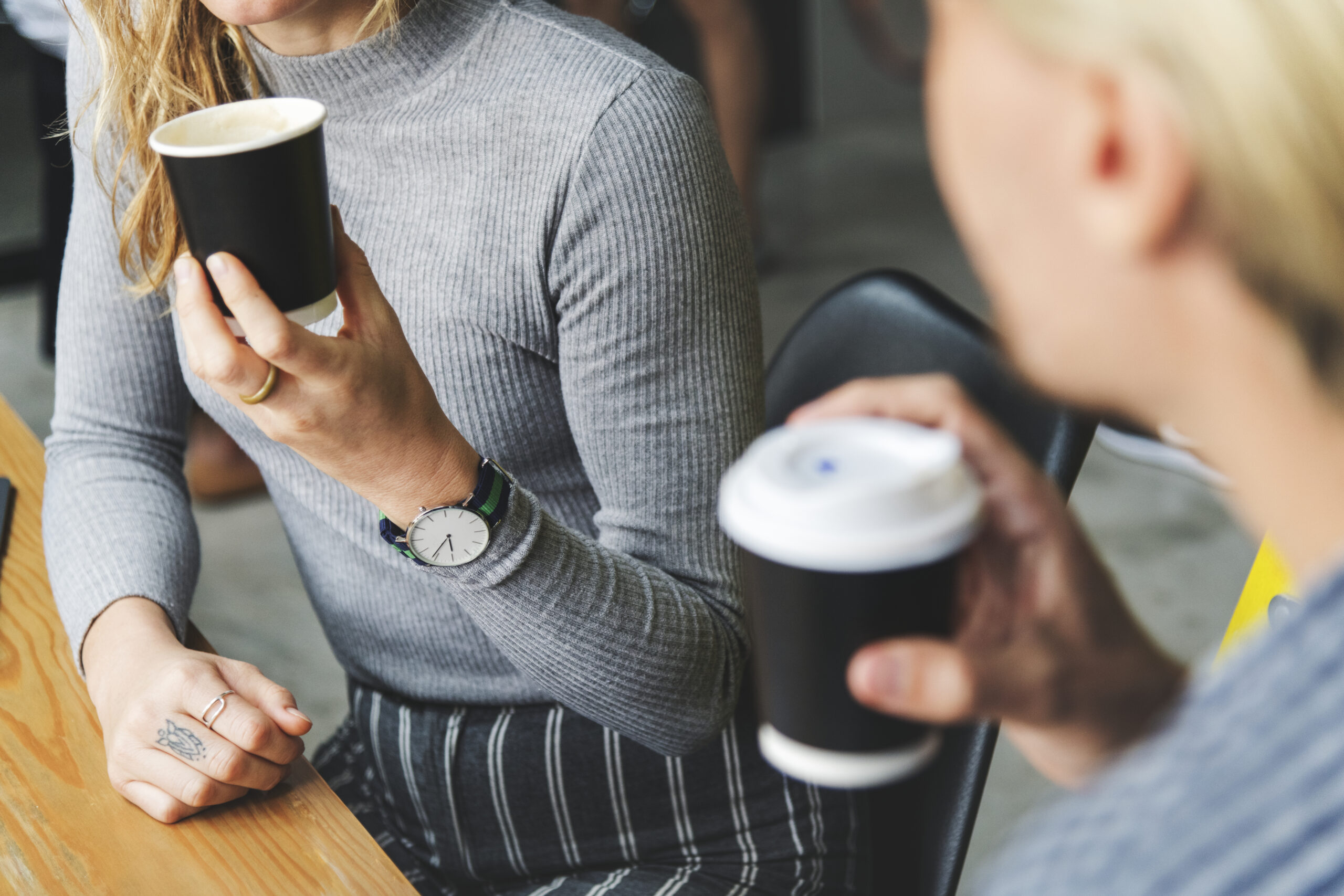 Two coffee cups on a desk with a notebook
